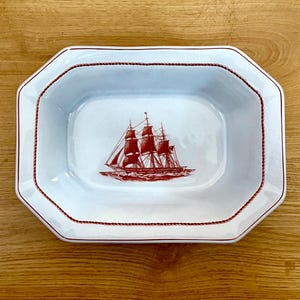 May include: White rectangular serving dish with a red nautical ship illustration. The dish has a red rope-like border and a slightly octagonal shape. The ship illustration is a detailed depiction of a tall sailing vessel.