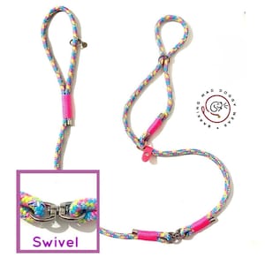 May include: A multi-colored rope leash featuring a vibrant pattern of blue, yellow, pink, and purple threads. The leash includes bright pink cord wraps, silver metal hardware, and a swivel connector. A logo reads BARKING MAD DOGGY WEAR.