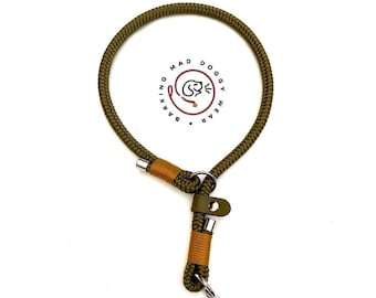 May include: An olive green rope dog collar featuring gold-colored thread accents, silver metal hardware, and a dark green leather tab with a snap button. The logo Barking Mad Doggy Wear is printed in the center with a circular dog icon.