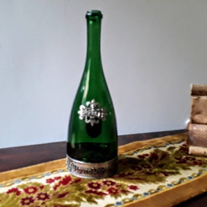 Antigua botella de cristal.  Botella de vidrio verde esmeralda con adornos de metall. Botella de vino vintage. Vintage botella de vino.