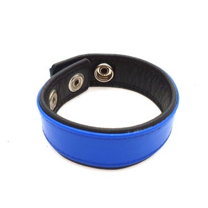 May include: A blue leather bracelet with black trim and silver metal snaps.