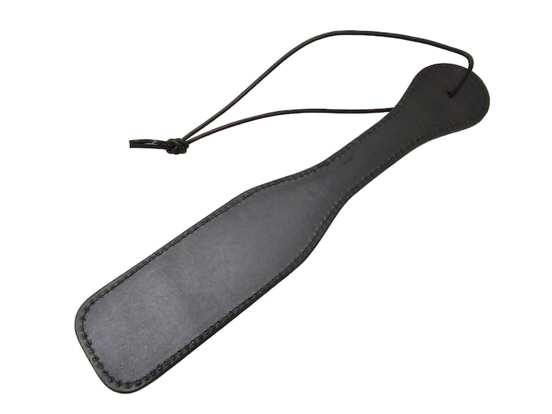 May include: A black leather paddle with a stitched edge and a loop handle.
