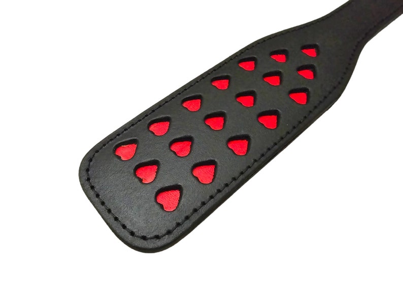 May include: Black leather paddle with red heart cutouts.