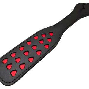 May include: Black leather paddle with red heart cutouts.