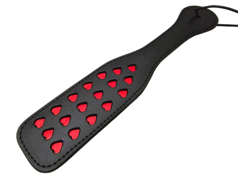 May include: Black leather paddle with red heart cutouts.