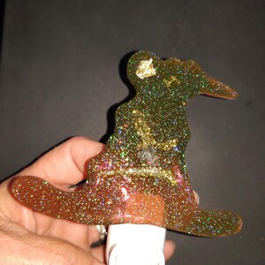 May include: A gold glitter nightlight shaped like a witch's hat. The nightlight has a white plug-in base.