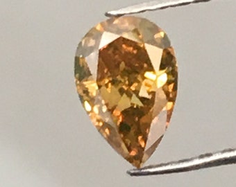 May include: A pear-shaped, brown diamond gemstone with a yellow hue, held by tweezers against a white background.