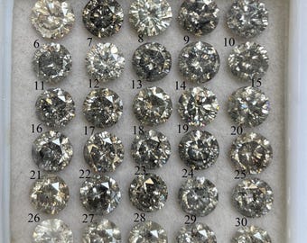 以下が含まれることがあります： 白いプラスチックトレイにセットされた、30個のラウンドカットダイヤモンドのコレクション。 ダイヤモンドの色は、明るいグレーから濃いグレーまで様々です。 各ダイヤモンドには、識別しやすいように1から30までの番号が付けられています。