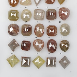 May include: Thirty loose, faceted, rough diamonds in various shapes and sizes. The diamonds are arranged in rows and numbered 1 through 30. The diamonds are a mix of brown, yellow, and clear colours.