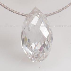 May include: A clear, faceted, teardrop-shaped crystal pendant hanging from a silver chain.