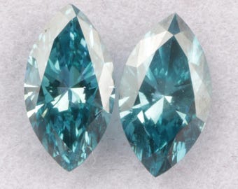 May include: Two teal-coloured marquise-cut gemstones. The gems are cut with multiple facets, creating a sparkling effect. The stones are set against a white background.