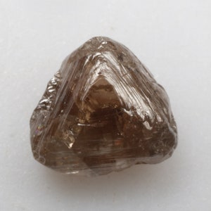 Puede incluir: Un cristal de diamante marrón, facetado y triangular.