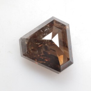Puede incluir: Una piedra preciosa de color marrón, facetada, de forma octogonal con un acabado rugoso y natural.