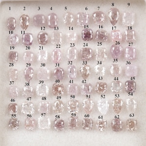 May include: A tray of 63 loose pink diamonds, numbered 1 through 63, arranged in rows. The diamonds are various shapes and sizes.