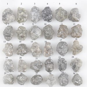 Puede incluir: Una colección de treinta diamantes en bruto sin cortar, cada uno con una forma única y diferentes tonos de gris. Los diamantes están numerados del 1 al 30, dispuestos en un patrón de cuadrícula sobre un fondo blanco. Estas gemas en bruto son para joyería.