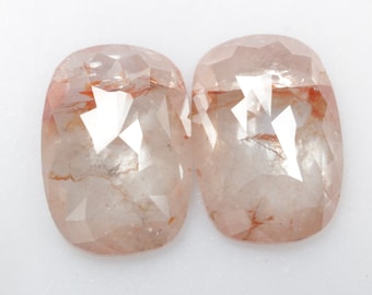 May include: Two clear, faceted, rose cut diamonds with a reddish-brown hue. The diamonds are set in a cushion shape.