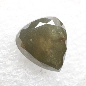 Pode incluir: Um diamante verde escuro em forma de coração com um corte facetado.