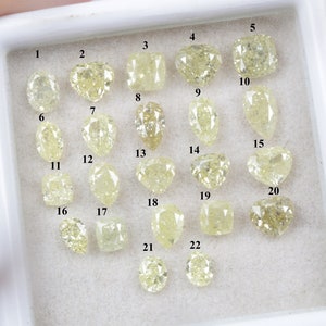 May include: Twenty-two loose yellow diamonds of various shapes and sizes, numbered 1 through 22, displayed in a white tray.