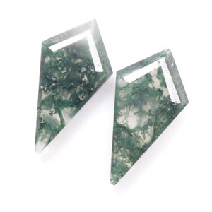Peut inclure: Deux cabochons d'agate mousse verte taillés en forme de cerf-volant. Les pierres sont translucides et présentent une bande blanche au centre.