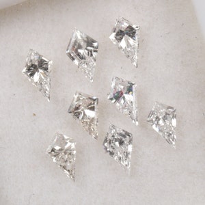 May include: Eight clear, faceted, kite-shaped diamonds on a white background.