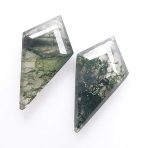 Peut inclure: Deux cabochons d'agate mousse verte taillés en forme de cerf-volant. Les pierres sont translucides et présentent un motif vert et blanc.