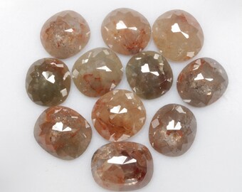 May include: A collection of ten loose, faceted, oval-shaped, rough diamonds. The diamonds are a mix of light brown and gray with a translucent appearance.