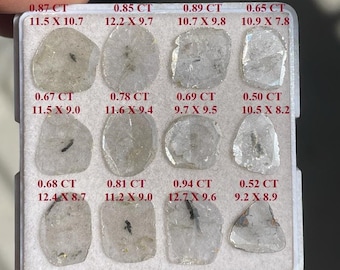 May include: A white tray with 12 clear, faceted gemstones. Each gemstone is labeled with its carat weight and dimensions in millimeters. The tray is made of plastic and has a white background.