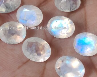 May include: A collection of oval-shaped moonstone gemstones with iridescent blue and white colors.