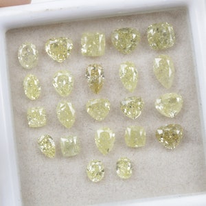 May include: A collection of 20 loose yellow diamonds of various shapes and sizes, displayed in a white tray.