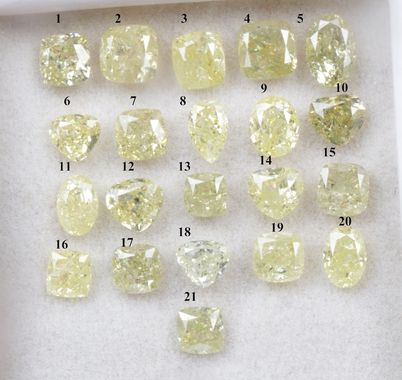 May include: Twenty-one loose yellow diamonds of various shapes and sizes, arranged in rows on a white surface. Each diamond is labelled with a number from 1 to 21.