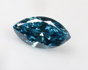 May include: A teal marquise-cut gemstone. The gem's many facets reflect light, creating a sparkling effect. The elongated shape has pointed ends. The gemstone is set against a white background.