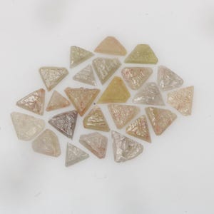 Peut inclure: Une collection de petites tuiles en mosaïque de forme triangulaire dans diverses nuances translucides de jaune pâle, de pêche douce et de blanc cassé. Chaque pièce présente une surface texturée, légèrement irisée, avec des veines internes subtiles.