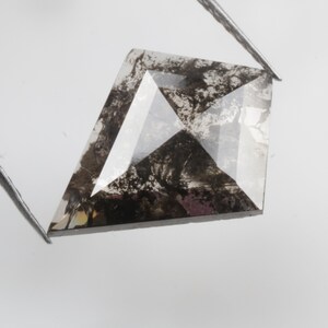 K&ouml;nnte beinhalten: Ein dunkelgrauer, facettierter, drachenf&ouml;rmiger Diamant mit Einschl&uuml;ssen.