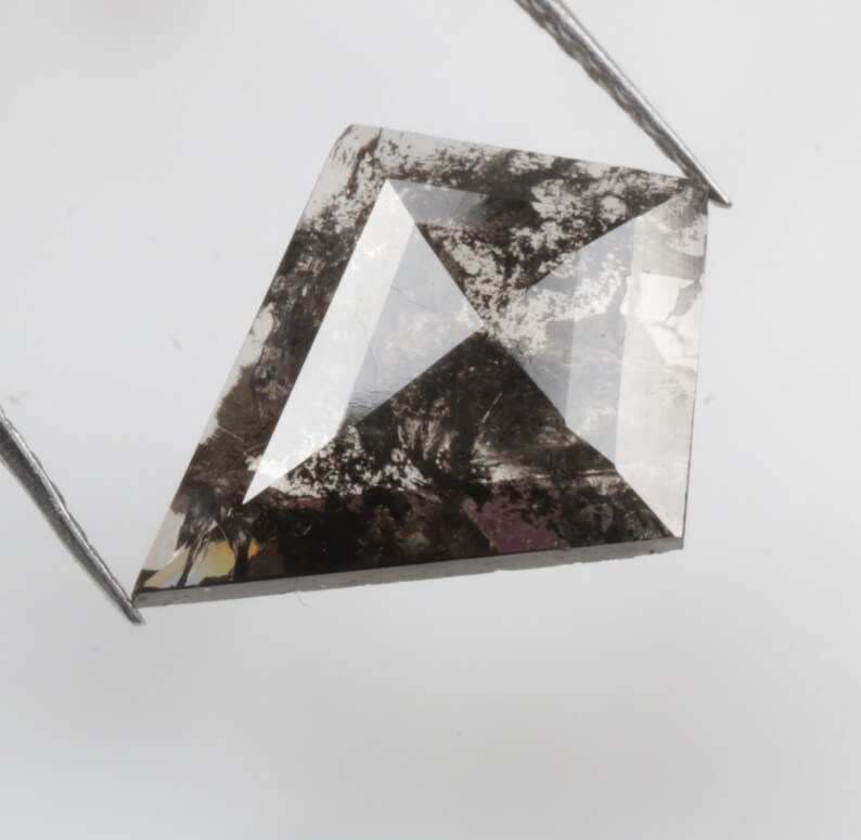 K&ouml;nnte beinhalten: Ein dunkelgrauer, facettierter, drachenf&ouml;rmiger Diamant mit Einschl&uuml;ssen.
