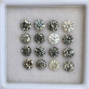 May include: A white tray with 15 round, gray diamonds of various shades. The diamonds are arranged in three rows of five.