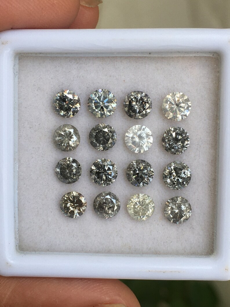 May include: A white tray with 15 round, gray diamonds of various shades. The diamonds are arranged in three rows of five.