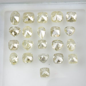 May include: Assortment of 21 loose, faceted, light yellow diamonds in a white tray. The diamonds are various shapes and sizes.