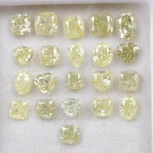 May include: A collection of 20 loose yellow diamonds of various shapes and sizes, displayed in a white box.