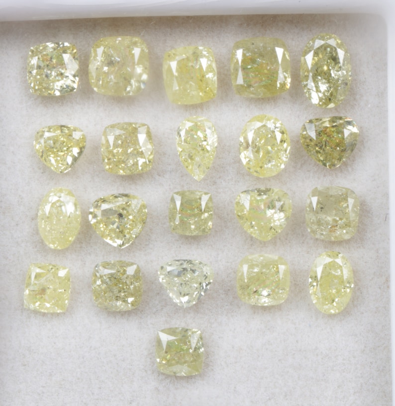 May include: A collection of 20 loose yellow diamonds of various shapes and sizes, displayed in a white box.
