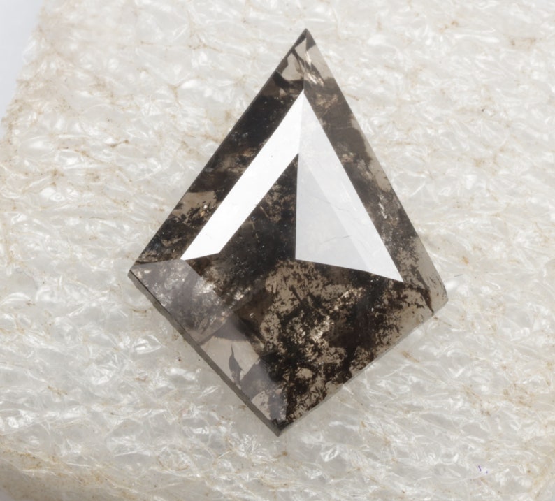 K&ouml;nnte beinhalten: Ein dunkelgrauer, dreieckiger Diamant mit einer wei&szlig;en, dreieckigen Facette in der Mitte.