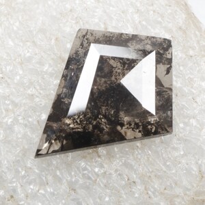 K&ouml;nnte beinhalten: Ein dunkelgrauer, facettierter, rauer Diamant mit wei&szlig;en Facetten. Der Diamant hat die Form eines rechten Winkels, aus dem ein Dreieck herausgeschnitten ist.