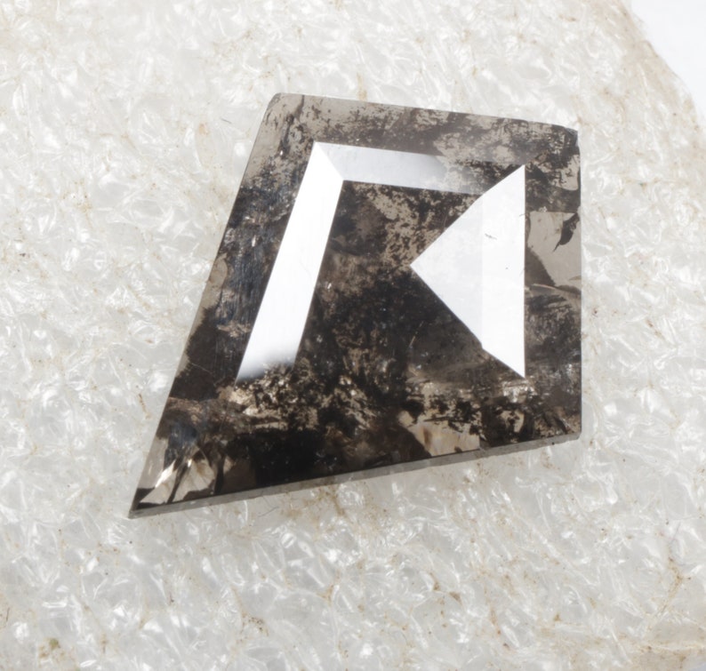 K&ouml;nnte beinhalten: Ein dunkelgrauer, facettierter, rauer Diamant mit wei&szlig;en Facetten. Der Diamant hat die Form eines rechten Winkels, aus dem ein Dreieck herausgeschnitten ist.
