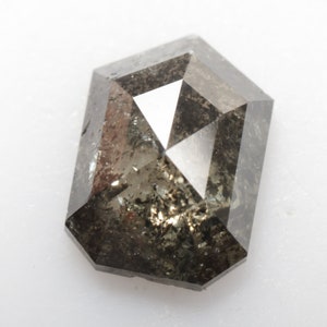 Peut inclure: Un diamant taillé en octogone de couleur gris foncé avec une surface facetée. Le diamant a une apparence brute et naturelle.
