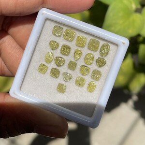 May include: A collection of yellow diamonds in a white tray. The diamonds are of various shapes and sizes.