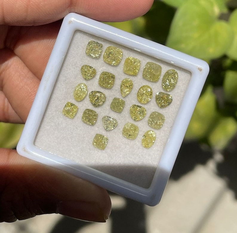 May include: A collection of yellow diamonds in a white tray. The diamonds are of various shapes and sizes.