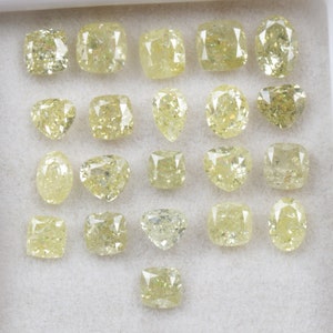 May include: A collection of 21 loose yellow diamonds of various shapes and sizes, displayed in a white tray.