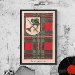 May include: A framed print of the MacGregor tartan with a crest featuring a tree and two swords. The tartan is red and green with a white border. The text "MacGregor" is printed below the tartan.