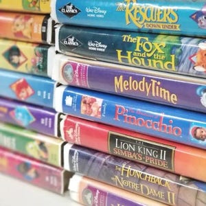 May include: A stack of Walt Disney Home Video VHS tapes featuring titles including The Rescuers Down Under, The Fox and the Hound, Melody Time, The Adventures of Pinocchio, The Lion King II Simba's Pride, and The Hunchback of Notre Dame II.
