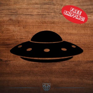 May include: Black silhouette of a UFO with oval windows. The image includes a red oval with the text "FREE SHIPPING!" on a wood grain background.