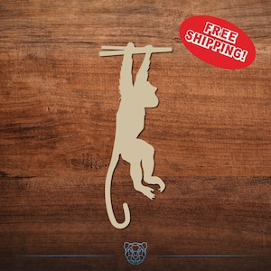 May include: A light tan monkey silhouette hanging from a wooden bar. The monkey is suspended against a dark brown wood grain background. A red oval with the text "FREE SHIPPING!" is in the upper right corner.